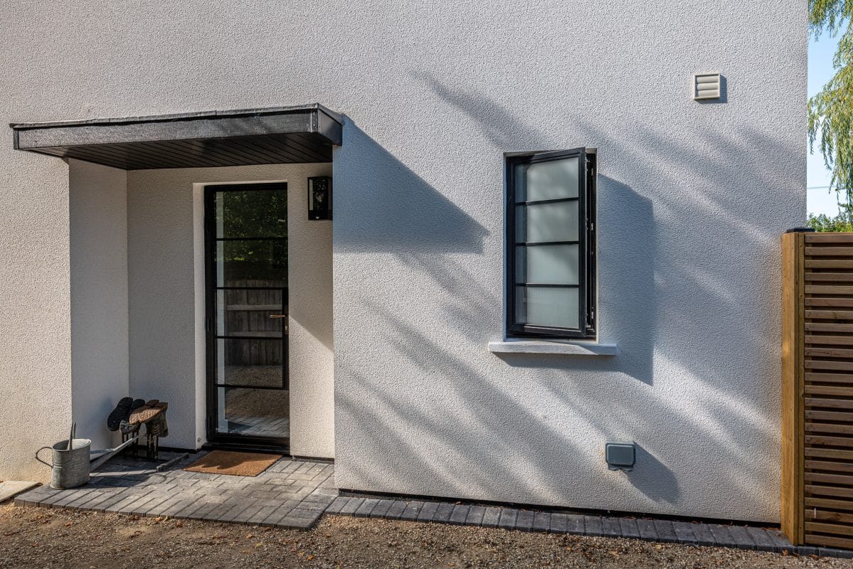 Black steel look door with boots and watering can next to partially open bathroom window