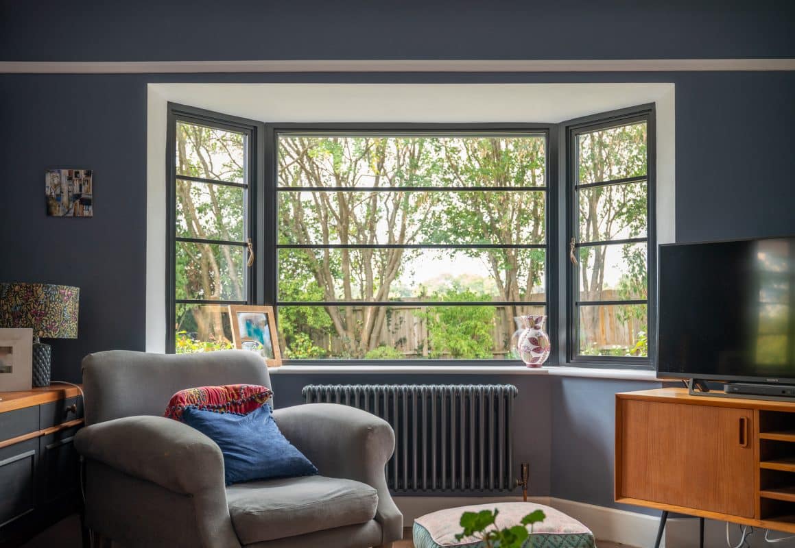 Picture of an Art-Deco inspired living room with Aluco steel look window and trees in the background