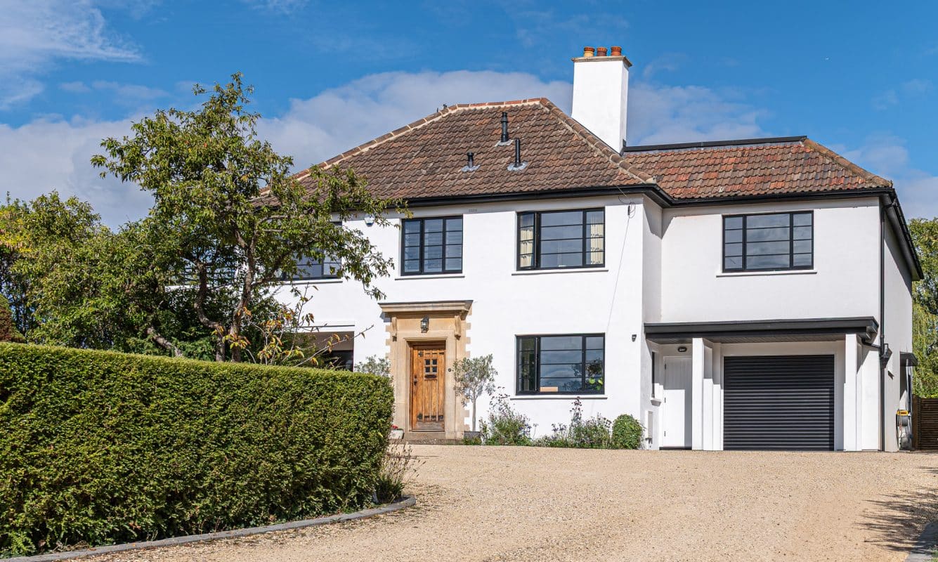 black steel look windows at the front elevation of a period house with hedge and driveway