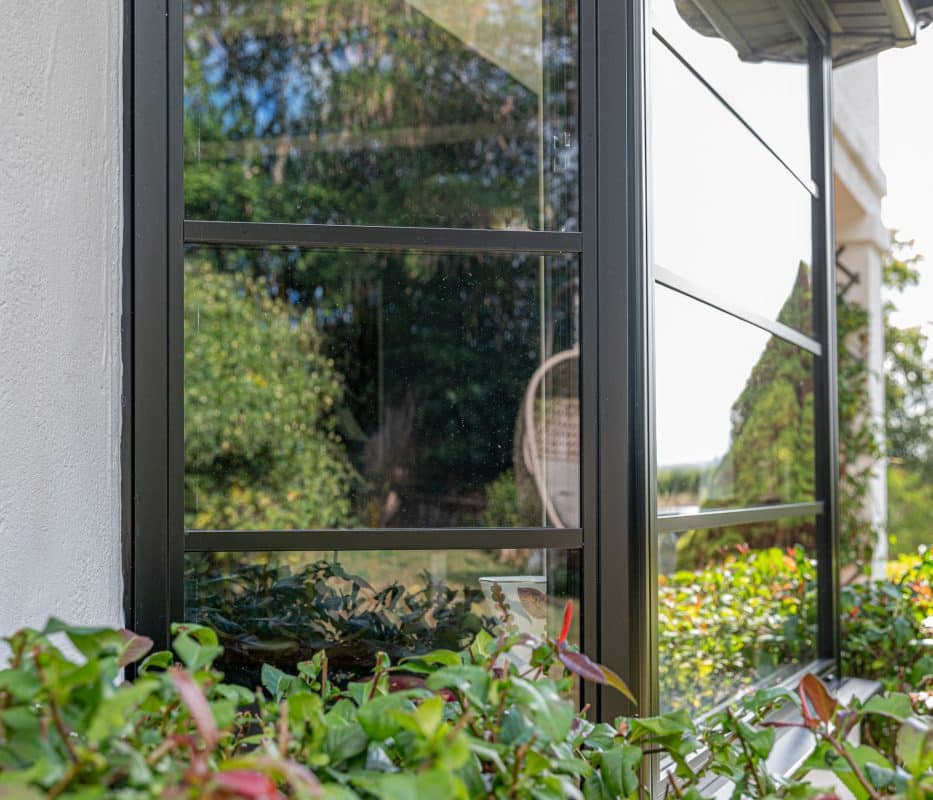 close up of aluco steel look window with hedge in front