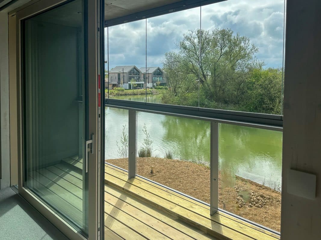 Solarlux glass balustrade system in a bedroom to a timber-decked outside space. 