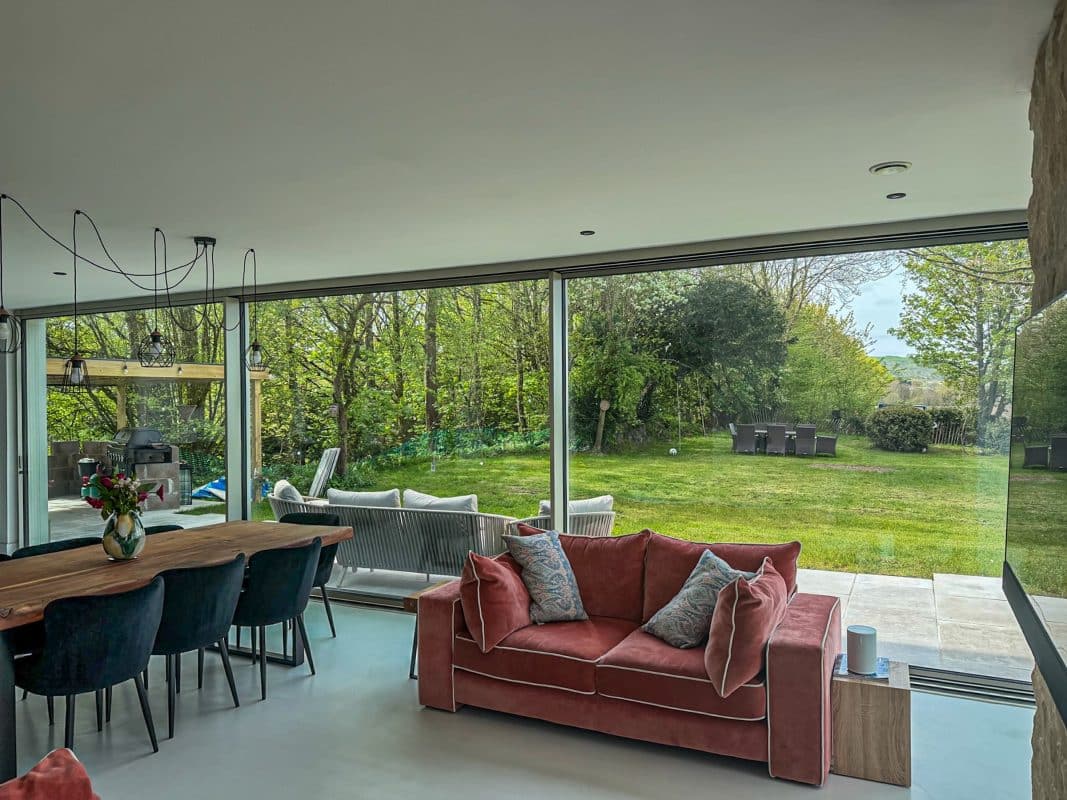 Solarlux Cero Corner Sliding Doors in a Contemporary New Build 8 grey sliding doors in contemporary kitchen with red sofa and stylish dining table